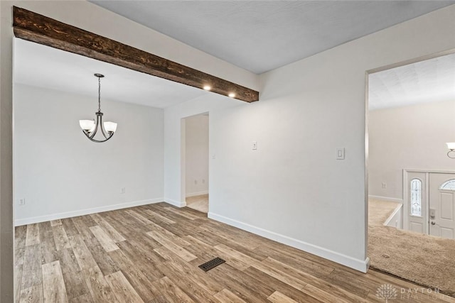 unfurnished room featuring an inviting chandelier, hardwood / wood-style flooring, and beamed ceiling