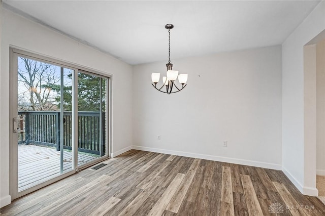 empty room with hardwood / wood-style flooring and an inviting chandelier