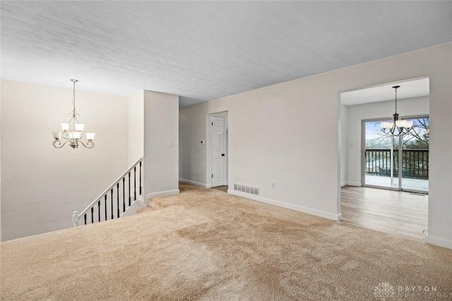 unfurnished room featuring light carpet and a chandelier