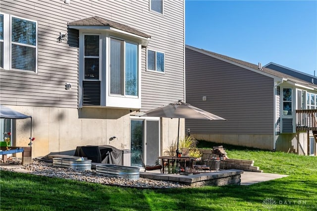 rear view of house with a patio and a lawn