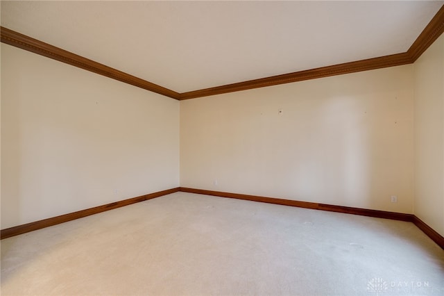 unfurnished room with baseboards, ornamental molding, and light carpet