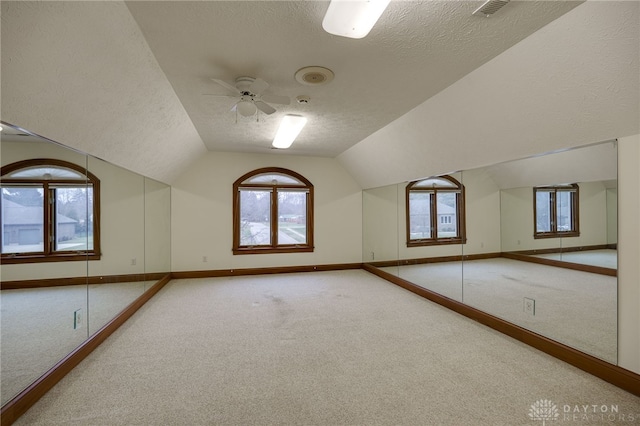 bonus room with a textured ceiling, lofted ceiling, visible vents, ceiling fan, and carpet