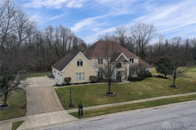 traditional-style house with stucco siding, fence, an attached garage, driveway, and a front yard
