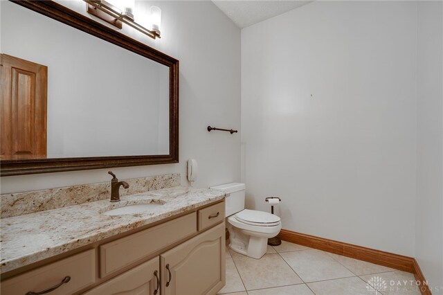 bathroom with baseboards, toilet, tile patterned flooring, and vanity
