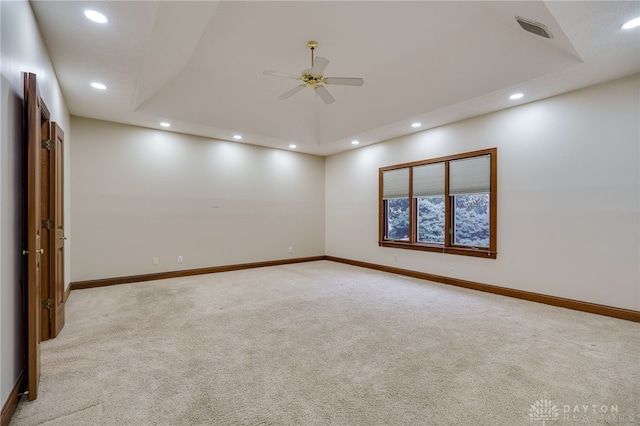 spare room with a tray ceiling, baseboards, and ceiling fan