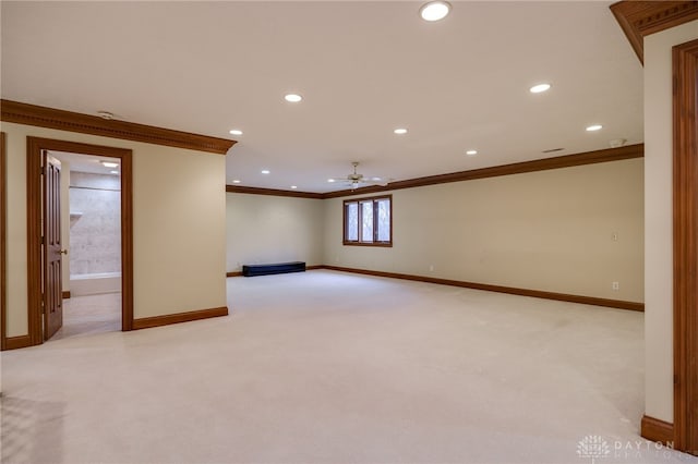 below grade area featuring light carpet, crown molding, baseboards, and ceiling fan