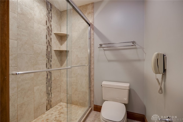 bathroom featuring baseboards, toilet, and a stall shower