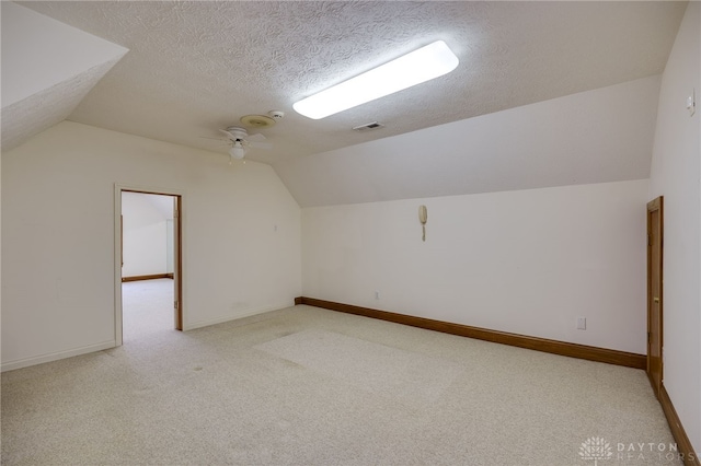 bonus room featuring a textured ceiling, baseboards, ceiling fan, vaulted ceiling, and light colored carpet