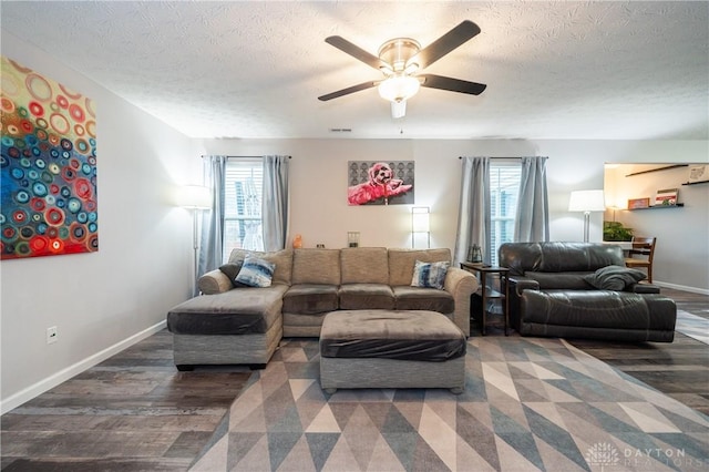 living room with ceiling fan, dark wood-type flooring, and a textured ceiling