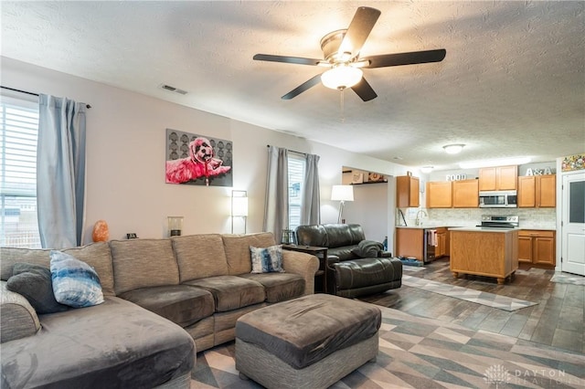 living room with ceiling fan, dark wood-type flooring, sink, and a textured ceiling