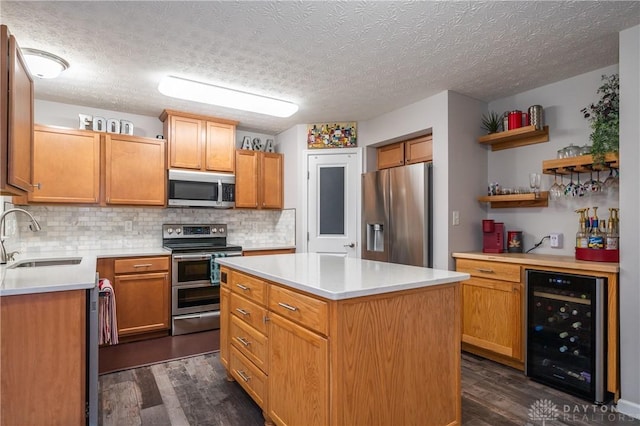 kitchen with appliances with stainless steel finishes, sink, beverage cooler, dark hardwood / wood-style flooring, and a center island