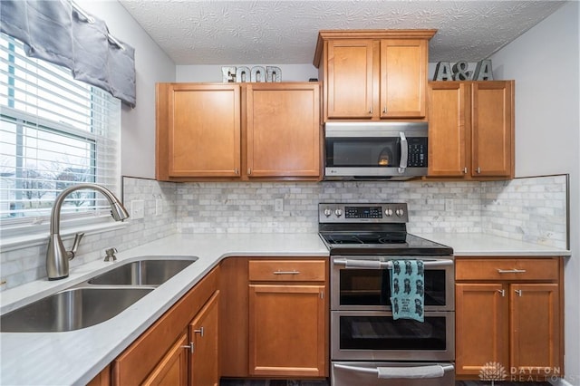 kitchen featuring sink, backsplash, stainless steel appliances, and a textured ceiling