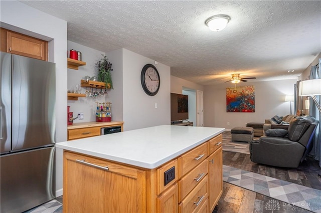 kitchen featuring a kitchen island, a textured ceiling, stainless steel fridge, and light wood-type flooring