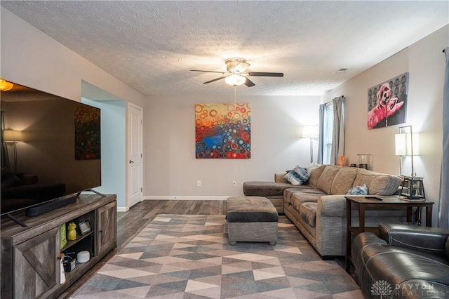 living room with dark hardwood / wood-style flooring, ceiling fan, and a textured ceiling