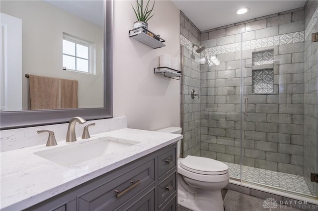 bathroom featuring vanity, a shower with shower door, and toilet