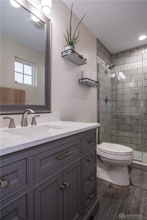 bathroom with vanity, toilet, a shower with shower door, and hardwood / wood-style floors