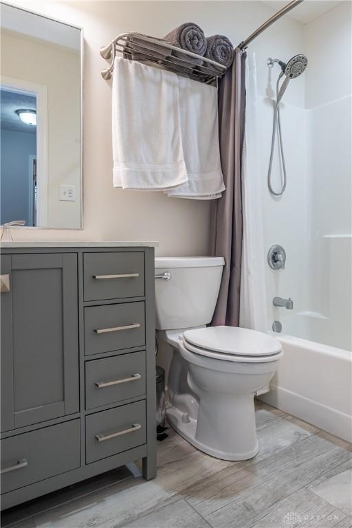 full bathroom featuring shower / bathtub combination with curtain, vanity, hardwood / wood-style floors, and toilet