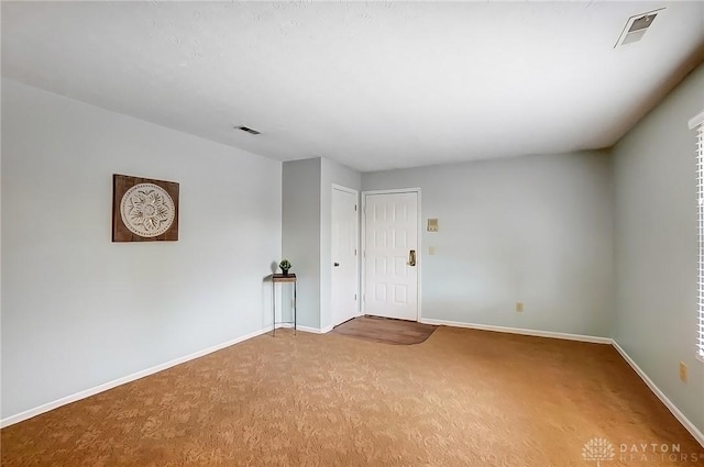 empty room featuring carpet floors, visible vents, and baseboards