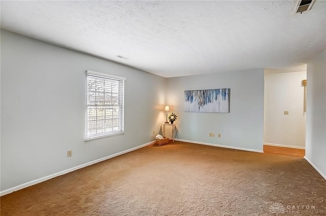 carpeted empty room with visible vents, a textured ceiling, and baseboards