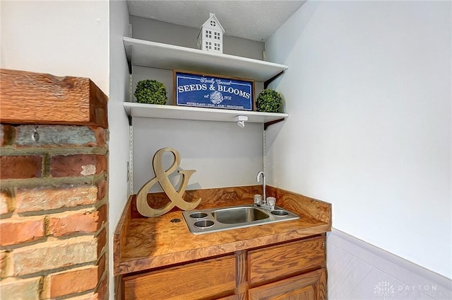 interior space with a textured ceiling, wainscoting, and a sink