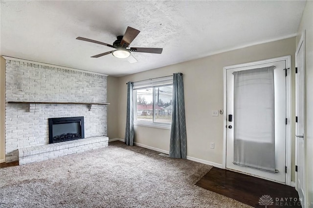 unfurnished living room featuring a brick fireplace, ceiling fan, a textured ceiling, and carpet flooring