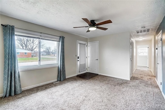 carpeted spare room with ceiling fan and a textured ceiling