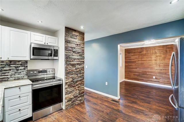 kitchen with appliances with stainless steel finishes, white cabinets, decorative backsplash, dark wood-type flooring, and a textured ceiling