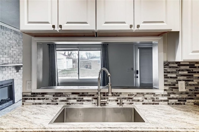 kitchen featuring sink, decorative backsplash, light stone countertops, and white cabinets