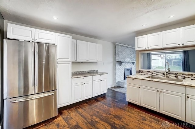 kitchen featuring white cabinetry, sink, dark hardwood / wood-style floors, and stainless steel refrigerator