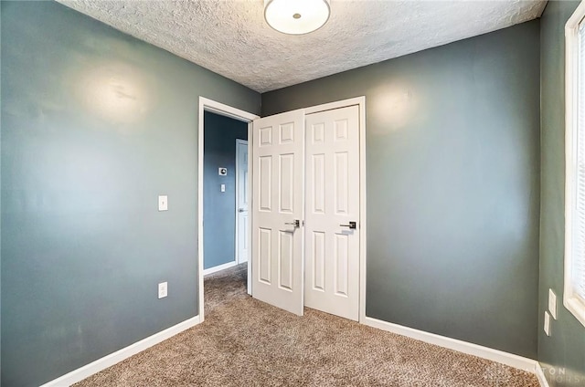 unfurnished bedroom with carpet flooring, a textured ceiling, and a closet