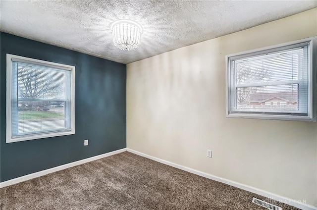 carpeted empty room with a textured ceiling