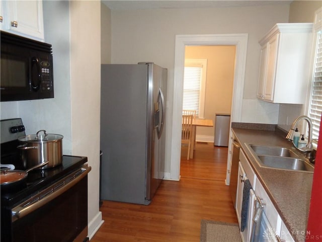 kitchen with stainless steel appliances, sink, hardwood / wood-style floors, and white cabinets