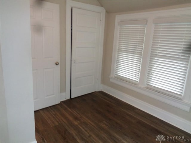 unfurnished bedroom with dark wood-type flooring and a closet