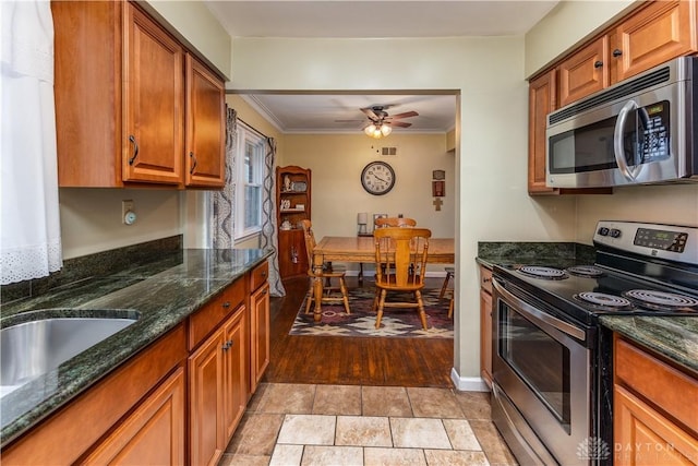 kitchen with dark stone countertops, crown molding, stainless steel appliances, and ceiling fan