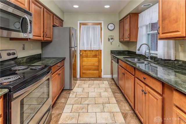 kitchen featuring stainless steel appliances, sink, and dark stone counters