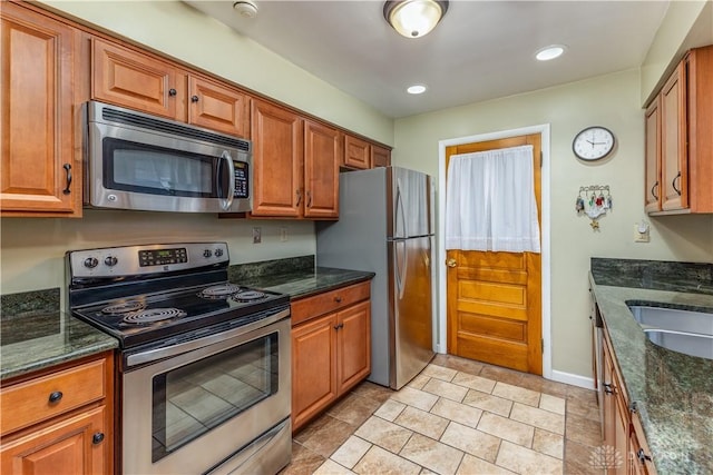 kitchen with stainless steel appliances, sink, and dark stone counters