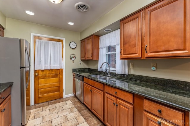 kitchen with stainless steel appliances, sink, and dark stone countertops