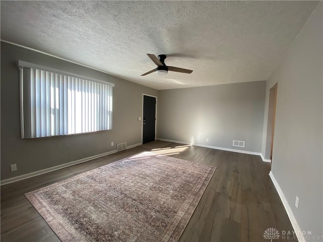 empty room with dark hardwood / wood-style flooring, a textured ceiling, and ceiling fan