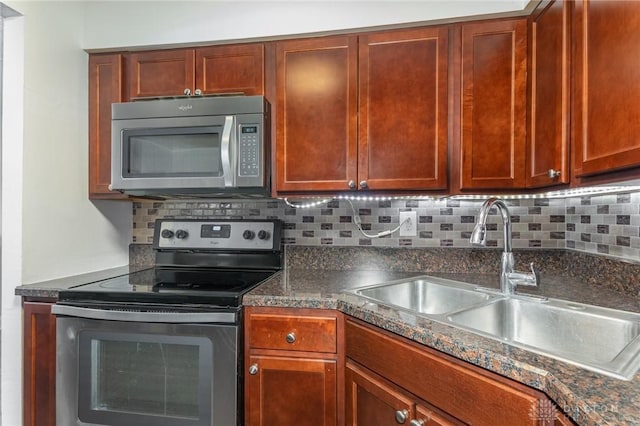 kitchen featuring stainless steel appliances, tasteful backsplash, sink, and dark stone counters