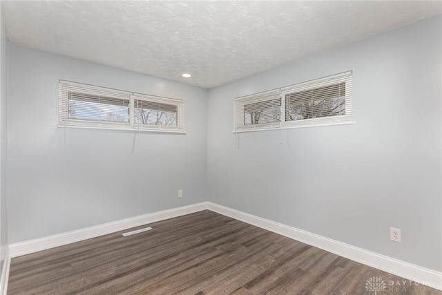 empty room with dark hardwood / wood-style flooring and a textured ceiling