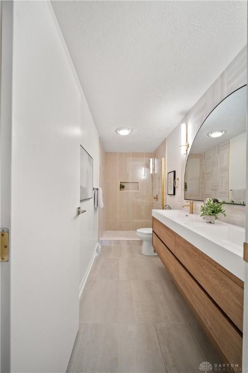 4260 Penny Pike, German Twp, OH 45502 - full bathroom featuring toilet, tiled shower, a textured ceiling, and double vanity