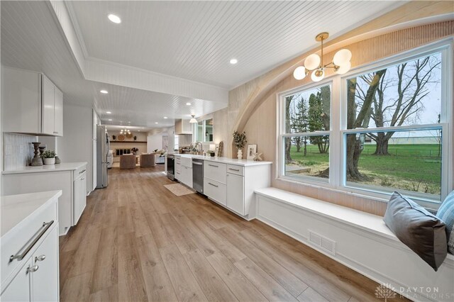 4260 Penny Pike, German Twp, OH 45502 - kitchen with appliances with stainless steel finishes, white cabinetry, light countertops, a chandelier, and light wood-style flooring