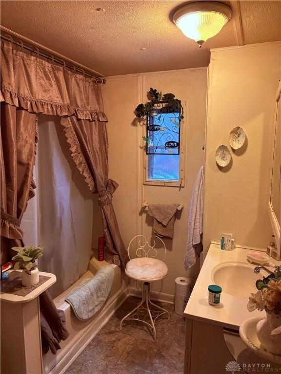 bathroom featuring shower / bath combo, vanity, and a textured ceiling