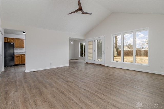 unfurnished living room with ceiling fan, high vaulted ceiling, and light hardwood / wood-style flooring