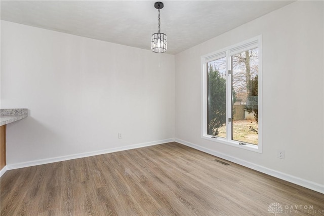 unfurnished dining area with a chandelier and light wood-type flooring