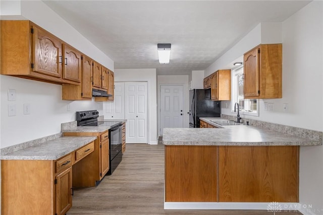 kitchen featuring light hardwood / wood-style floors, sink, black appliances, and kitchen peninsula