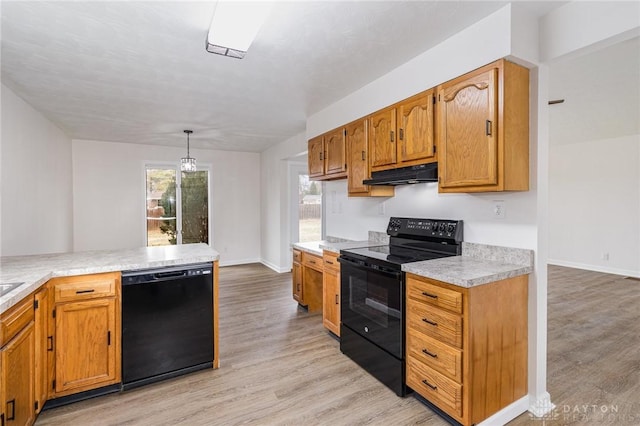 kitchen featuring pendant lighting, kitchen peninsula, light hardwood / wood-style floors, and black appliances