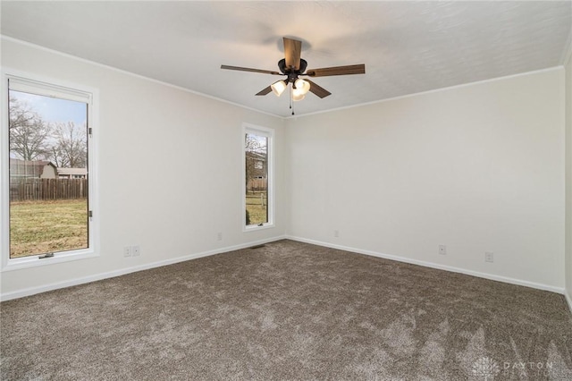 empty room with crown molding, ceiling fan, and dark carpet