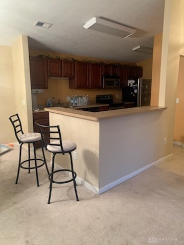 kitchen featuring stainless steel appliances, a breakfast bar, and kitchen peninsula