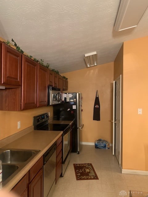 kitchen with sink, vaulted ceiling, appliances with stainless steel finishes, and a textured ceiling